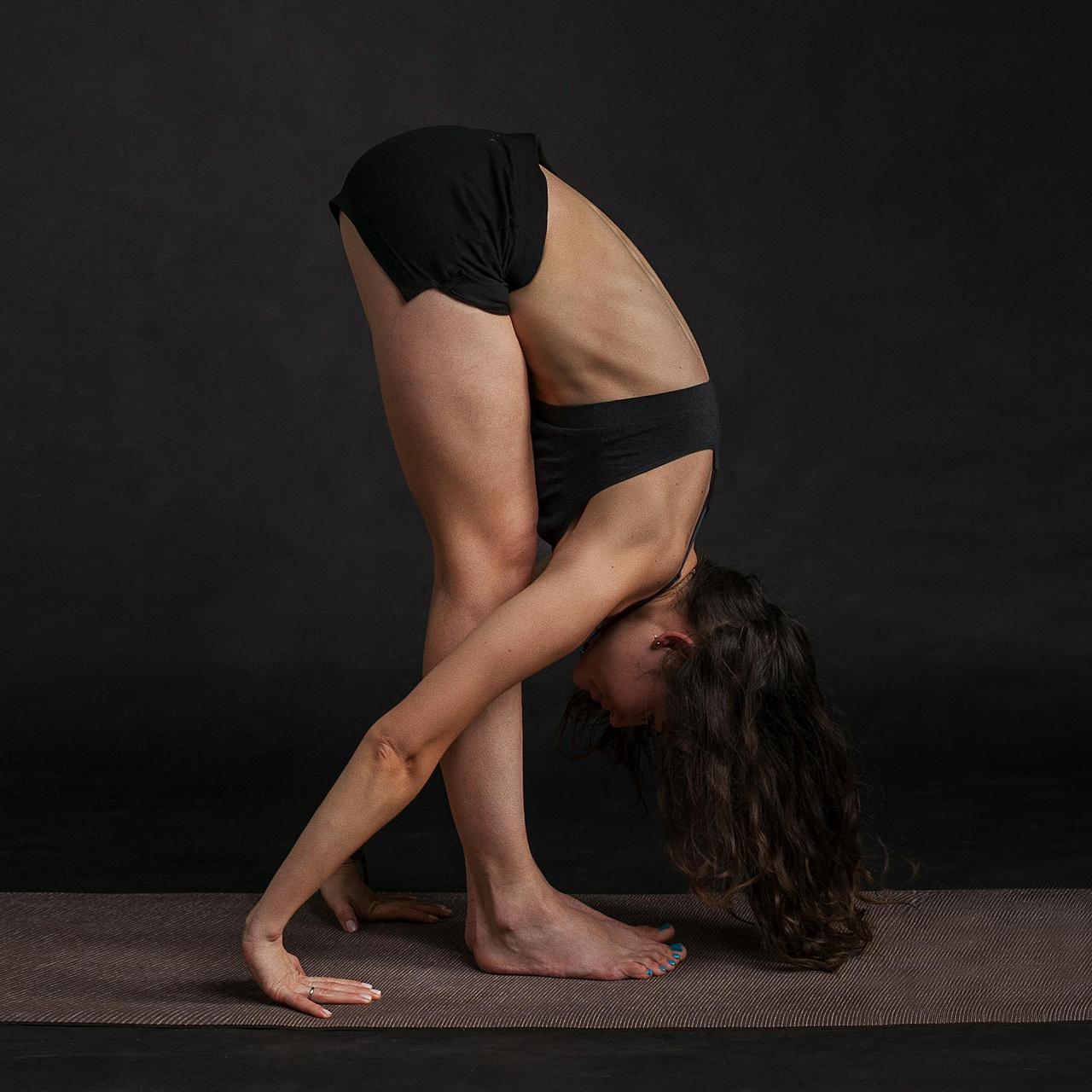 Woman performing forward bend yoga pose on mat, showcasing flexibility and focus.